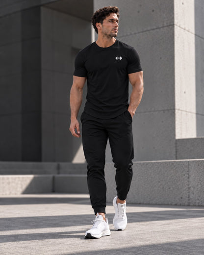 Black Form Muscle Tee, full-body walking view with black joggers and white sneakers.