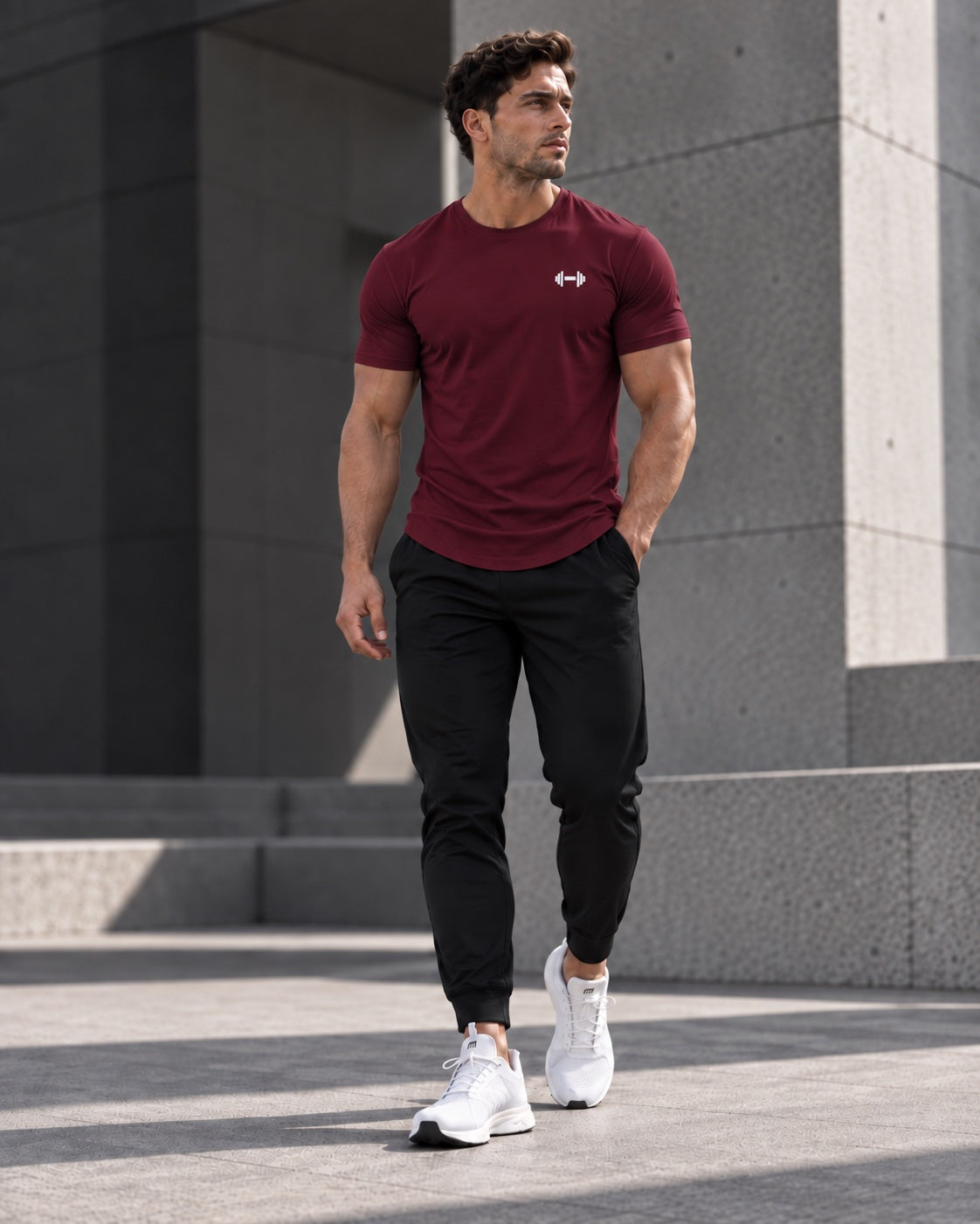Form Muscle Tee in Burgundy, full-body walking view showing the curved hem, black joggers and white sneakers.